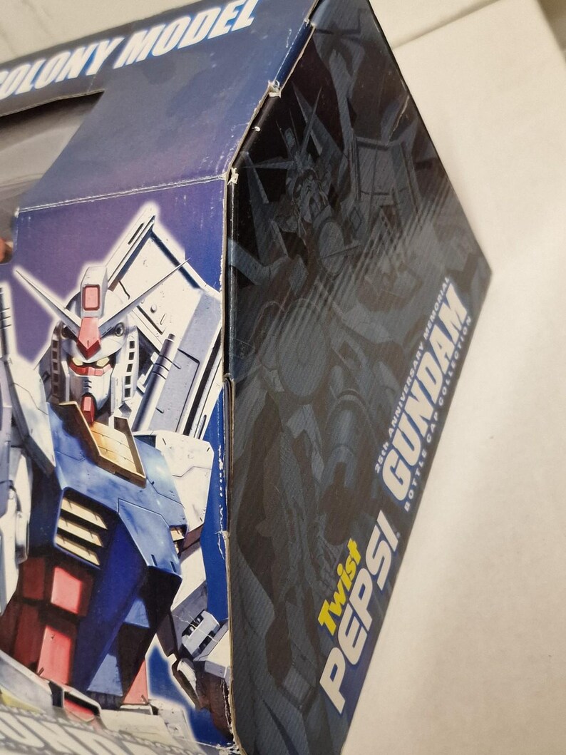 May include: A blue and white box featuring a Gundam robot illustration. The box has the text "COLONY MODEL" and "Twist Pepsi Gundam 25th Anniversary Memorial Bottle Cap Collection". The robot is primarily blue, red, and white.