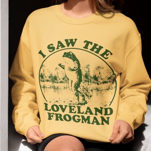 May include: A yellow sweatshirt with a green graphic of a frog and the text "I saw the Loveland Frogman".