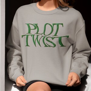 May include: A grey sweatshirt with the words "PLOT TWIST" printed in green on the front.