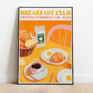 May include: A framed illustration of a breakfast scene with a table set for a meal. The image features a basket of croissants, eggs, coffee, and a bag of Brazilian coffee. The text "BREAKFAST CLUB MEETING EVERYDAY 7 AM-10 AM" is at the top.