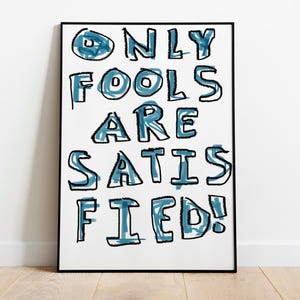 May include: A framed print with the text "ONLY FOOLS ARE SATISFIED!" in blue and black lettering on a white background.