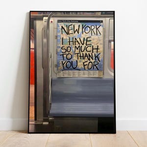 May include: A black and white photograph of a subway car interior with a sign that reads "New York I have so much to thank you for".
