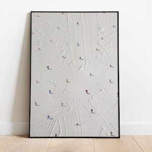 May include: Framed art print featuring an abstract textured white background with numerous tiny figures, likely skiers or snowboarders, scattered across the surface. The figures are in various colors, adding pops of vibrancy to the artwork. The frame is black.