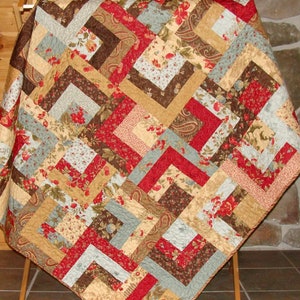 May include: A quilt with a patchwork design featuring various floral patterns in shades of red, brown, beige, and blue. The quilt is made with a variety of fabrics, including paisley and floral prints.