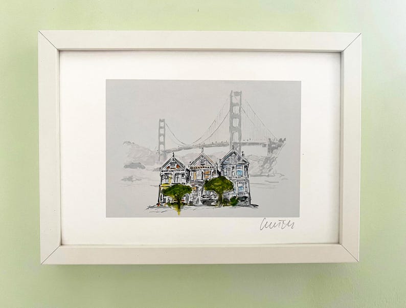 May include: A framed watercolour painting of three colourful Victorian houses with a green tree in front of them. The Golden Gate Bridge is in the background. The painting is signed "Leurrer".