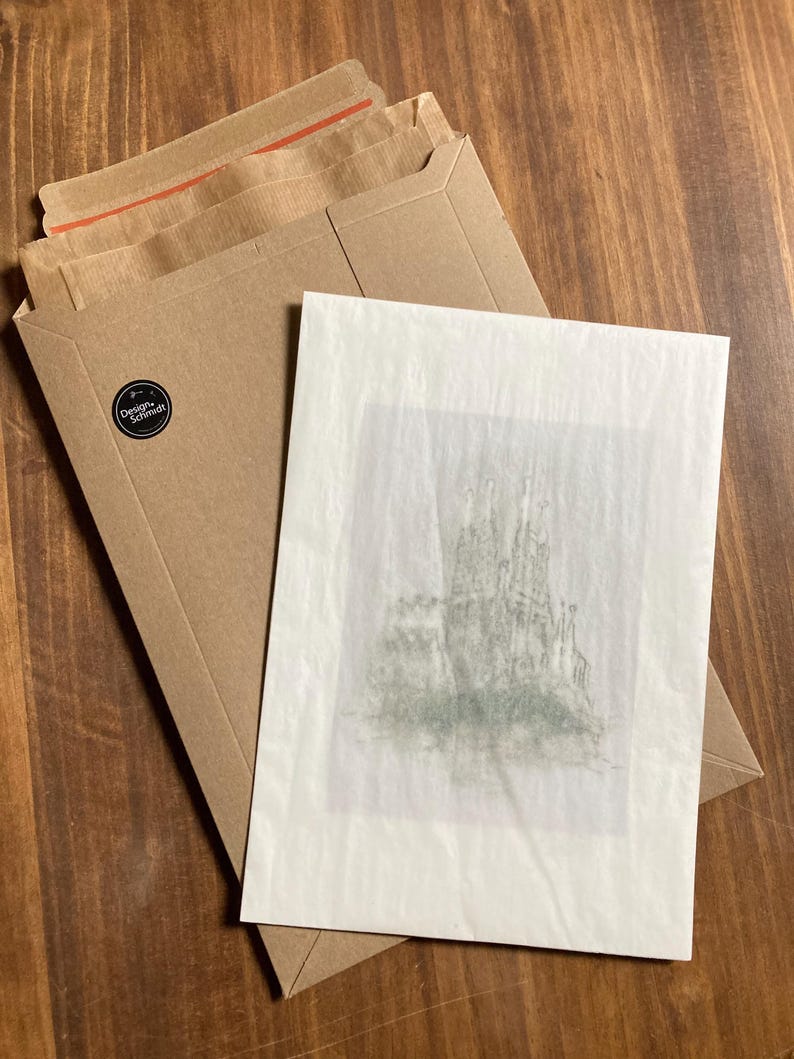 May include: A white card with a black and white drawing of a castle on it. The card is sitting on a brown paper envelope.