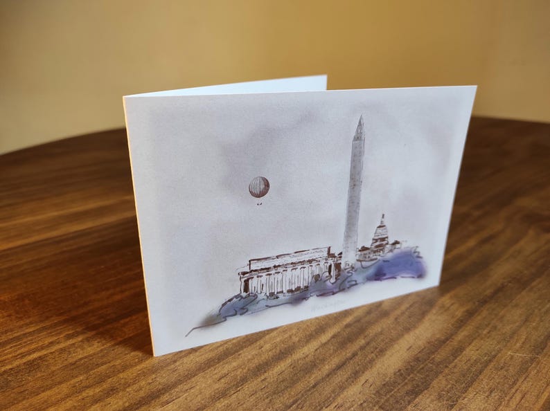 May include: A watercolor illustration of the Washington Monument and the Lincoln Memorial in Washington, D.C. A hot air balloon is in the sky above the monuments.