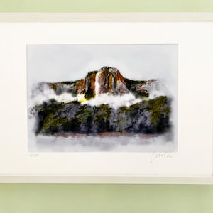 May include: A framed watercolour painting of a mountain with a waterfall cascading down the side. The mountain is surrounded by trees and fog. The painting is signed "Jenita" in the bottom right corner.