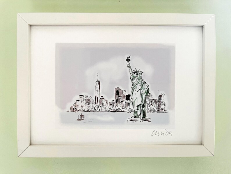 May include: A black and white sketch of the Statue of Liberty and the New York City skyline. The image is framed in a white frame and signed "Cleindy".