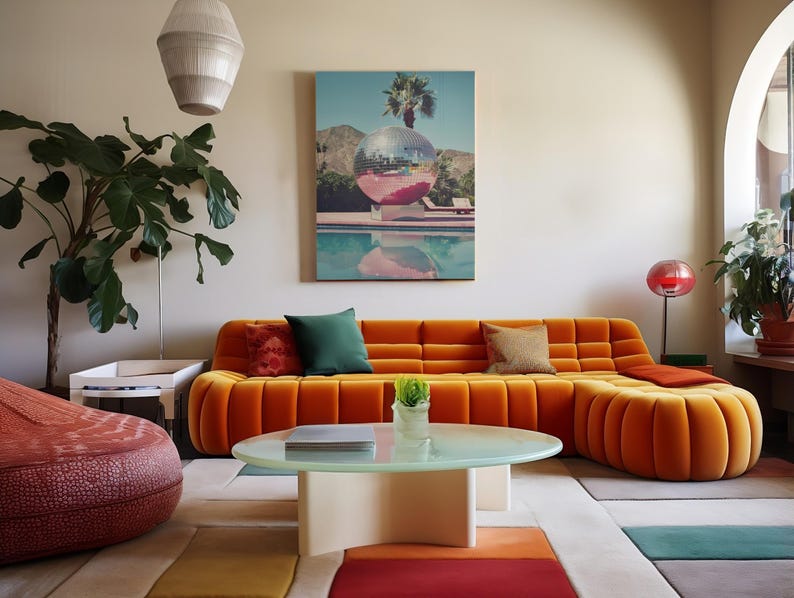 May include: A large orange sectional sofa with tufted cushions sits in a living room with a white coffee table and a green plant. A painting of a palm tree and a pool hangs on the wall.