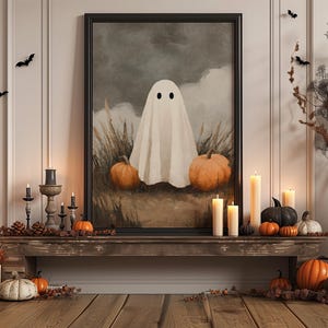 Pode incluir: Uma exibição temática de Halloween com uma obra de arte emoldurada de um fantasma, ladeada por abóboras e velas. A obra de arte está centrada numa prateleira de madeira rústica, com morcegos decorativos e folhagem seca. A paleta de cores inclui laranja, preto e branco.