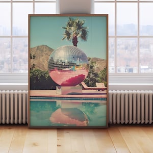 May include: A vintage-style photograph of a large disco ball in a swimming pool with a palm tree in the background.