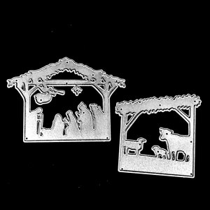 May include: Two die-cut metal Christmas nativity scene shapes. One depicts the holy family in a stable, the other shows animals. The shapes are silver and have a detailed, cutout design, perfect for crafting or scrapbooking projects.