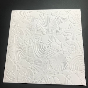 May include: White embossed paper with a repeating pattern of seashells, starfish, and bubbles.