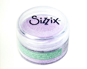 May include: A small clear jar with a purple powder inside. The jar has a black label with the word "Sizzix" and the text "POUDRE A EMBOSSER OPAQUE I POLVO DE ER FUSTELLATURA I MATOBAR ПУДРА ДЛЯ I PO OPACO DE ALTO RELEVO PRAGEPULVERI" in multiple languages.