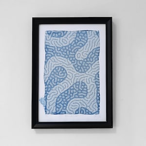 Pode incluir: Uma impressão emoldurada de um design abstrato em azul e branco. O design apresenta um padrão de linhas brancas que se movem em espiral sobre um fundo azul.