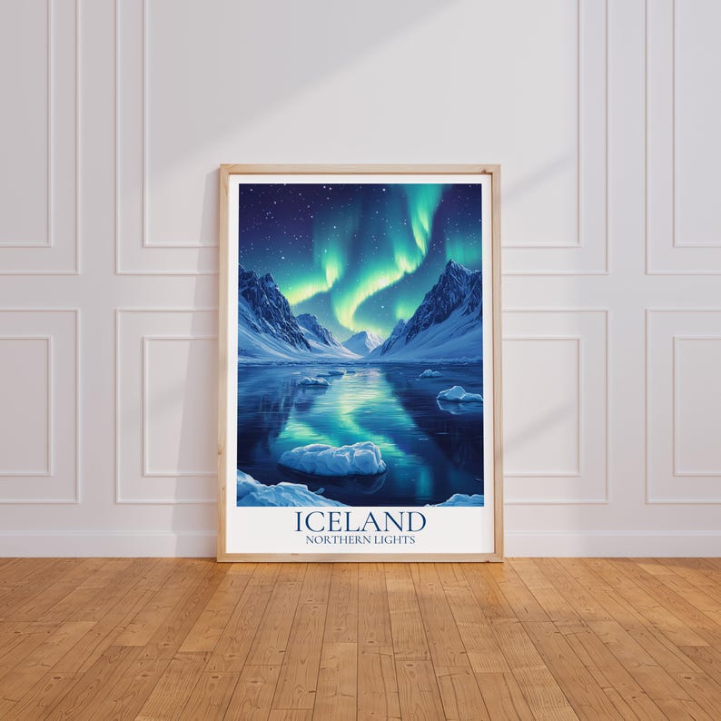 May include: Framed print of the Northern Lights in Iceland. The image shows a tranquil scene with snow-covered mountains, a reflective lake, and vivid green and blue aurora borealis. The print is in a wooden frame and has the word "ICELAND" at the bottom.