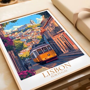 May include: A framed art print depicting Lisbon, Portugal, with a yellow tram on a steep street. The image shows vibrant buildings, a blue sky, and the words "LISBON PORTUGAL" at the bottom. The print is presented in a wooden frame.