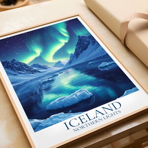 May include: A framed print featuring the Northern Lights over Iceland. The image shows a vivid aurora borealis display above a snowy terrain with mountains and water. The print is in a wooden frame and has the text "ICELAND NORTHERN LIGHTS".