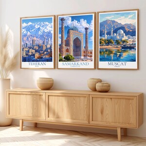 Peut inclure: Trois impressions d'art encadr&eacute;es repr&eacute;sentant des paysages urbains. Les impressions repr&eacute;sentent T&eacute;h&eacute;ran, Samarkand et Mascate, chacune avec une architecture et un arri&egrave;re-plan naturel uniques. Les impressions sont dans des cadres en bois et sont expos&eacute;es au-dessus d'un meuble en bois.