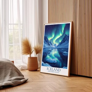 May include: A framed print featuring the Northern Lights over Iceland. The artwork shows a vivid aurora borealis above a snowy landscape and a reflective lake. The print is in a wooden frame, with the text "ICELAND NORTHERN LIGHTS" at the bottom.