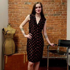 May include: A sleeveless black dress with a red geometric pattern. The dress has a v-neck and a collar.