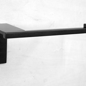 May include: Black metal toilet paper holder mounted on a white wall. The holder has a square base and a rectangular arm.