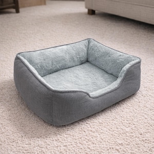 May include: A gray pet bed with a soft, plush interior and a textured exterior. The bed has a rectangular shape with raised sides for added comfort and security. The interior is a light blue-gray color.
