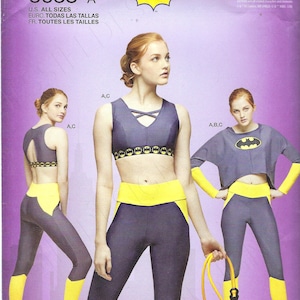 May include: A sewing pattern for a Batgirl costume. The pattern includes instructions for a crop top, leggings, and a cape. The pattern is printed on a purple background with a yellow Batgirl logo.