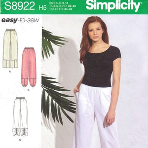 May include: Simplicity sewing pattern S8922 for women's pants. The pattern includes multiple styles, including wide-leg pants with gathered hems. The image shows a woman wearing white pants and a black top. The pattern is easy-to-sew.