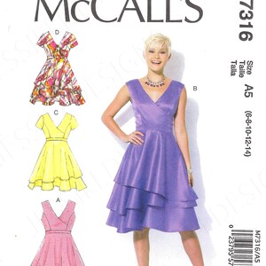 May include: A sewing pattern for a dress with a V-neckline and a layered skirt. The pattern is for sizes 6-8-10-12-14 and is called McCall's M7316.