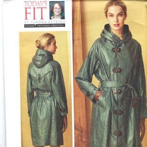 May include: A sewing pattern for a hooded raincoat with a belt and button closures. The pattern is from Vogue Patterns and is designed by Sandra Betzina. The pattern number is V1564.