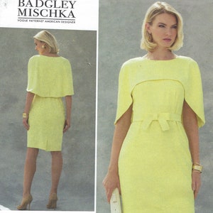 Puede incluir: Un vestido amarillo con una capa a juego y un cinturón. El vestido tiene una silueta ajustada y un escote redondo. El número de patrón es V1579 y la talla es A5 (6-8-10-12-14).