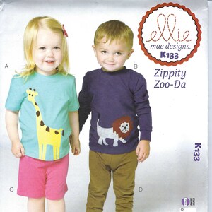 May include: A sewing pattern for children's clothing, featuring a giraffe and lion design. The pattern includes a light blue t-shirt with a yellow giraffe, pink shorts, a purple long-sleeve shirt with a lion, and brown pants. The text "Zippity Zoo-Da" is visible.