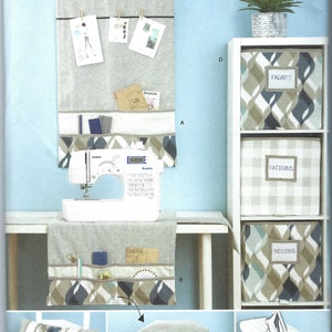 May include: A sewing pattern for a set of storage organizers. The pattern includes instructions for making a wall organizer, a sewing machine cover, a pillow, an ironing board cover, and three storage boxes. The boxes are labeled "Fabrics", "Patterns", and "Notions".