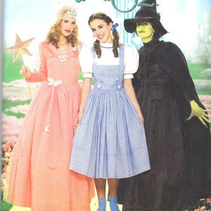 Op de afbeelding: Een naaipatroon voor het maken van kostuums uit The Wizard of Oz. Het patroon bevat instructies voor het maken van een roze jurk met sterren, een blauw-wit geruite jurk met een schort en een zwart-groen heksenkostuum. Het patroon is verkrijgbaar in de maten 6, 8, 10 en 12.