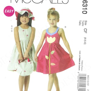 May include: A sewing pattern for two girls' dresses. The pattern is for sizes 4-5-6. The dresses are both sleeveless and have a floral print. One dress is pink with yellow flowers and the other is green with white flowers. The pattern is called McCall's M6310.