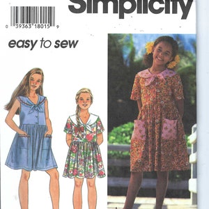 May include: Simplicity sewing pattern number 9554 for girls' dresses. The pattern includes three different styles: a blue denim dress with a sailor collar, a floral print dress with a sailor collar, and a floral print dress with a Peter Pan collar. The pattern is labeled "easy to sew".