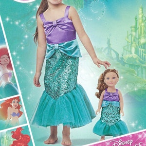 Puede incluir: Un patrón de costura Simplicity para un disfraz de la princesa Disney Ariel. El patrón incluye instrucciones para hacer un disfraz de sirena para un niño y una muñeca. El patrón es para las tallas 3-8. El patrón está impreso en un fondo rosa con una imagen de Ariel en la parte delantera.