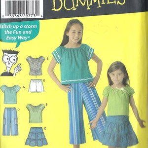 Puede incluir: Patrón de costura Simplicity 4206 para prendas separadas infantiles. El patrón incluye opciones para tops, pantalones cortos y una falda. La imagen muestra ejemplos de las prendas terminadas, incluyendo un top turquesa con ribete blanco y pantalones a rayas azules.