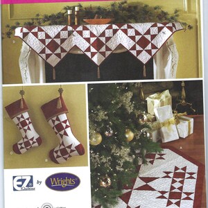 Könnte beinhalten: Eine Simplicity 3977 Schnittmusterhülle für weihnachtliche Stepparbeiten, die einen weißen und kastanienbraunen Kaminläufer mit Sternmuster und Quasten, zwei passende Weihnachtsstrümpfe sowie eine große achteckige Baumdecke zeigt.