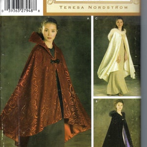 May include: Simplicity Vintage Closet sewing pattern featuring three cape designs. The main image shows a woman wearing a rust-colored cape with a swirl pattern and a black clasp. Additional capes are shown in cream and black.