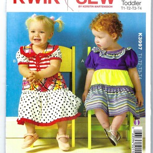May include: Kwik Sew pattern K3997 for toddler dresses. The pattern cover features two young children wearing colorful dresses. One dress has a polka dot skirt, and the other has a striped skirt. The text "KWIK SEW" is at the top.
