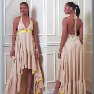 Könnte beinhalten: Ein Schnittmuster für ein halterloses Kleid mit einem High-Low-Saum. Das Kleid ist beige mit gelbem Besatz und wird an einem Model mit einem Pferdeschwanz gezeigt. Das Schnittmuster stammt von Vogue Patterns und wurde von Júlio César entworfen.