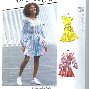 May include: A sewing pattern for a dress with three different views. The pattern includes a yellow dress with a tie waist, a pink and orange floral dress, and a striped dress with a belt. The pattern is for sizes 6-8-10-12-14. The pattern is from McCall's and includes the hashtag #LaurenMcCalls.