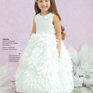 Puede incluir: Una niña con un vestido blanco con falda de pétalos y cuello Peter Pan. El vestido es de un patrón Simplicity, D0919, talla US 1 1/2-3. La imagen incluye el logotipo de Simplicity y texto sobre los materiales del vestido.