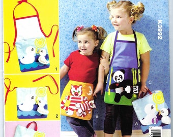 May include: A sewing pattern for children's aprons with three different designs. The designs include a panda, a tiger, and a pair of swans. The pattern is called "Kwik Sew" and the pattern number is K3992.