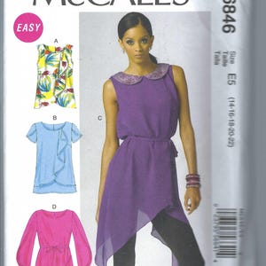 Könnte beinhalten: Nähmuster McCall's M6846, Größe E5 (14-16-18-20-22), für ein Oberteil mit Peter-Pan-Kragen, einer Rüsche und einer Schleife. Das Muster umfasst vier verschiedene Stile: ein Oberteil mit Blumenmuster, ein blaues Oberteil mit einer Rüsche, ein violettes Oberteil mit einer Schleife und ein rosa Oberteil mit langen Ärmeln und einer Schleife.