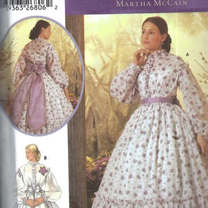 May include: A Simplicity sewing pattern envelope 5442 for The Fashion Historian by Martha McCain. The cover displays two dress variations with long sleeves, high collars, and floral prints, including a purple sash and a tiered skirt design.