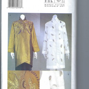 May include: A sewing pattern for wearable art by Marcy Tilton. The pattern features two long-sleeved tunic designs, one in a golden color with embroidered details and the other in white with a feather pattern. The pattern size is L-XL.